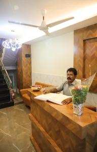 Ein Mann sitzt an einem Schreibtisch mit einem Dokument in der Unterkunft Hotel Pramila in Mumbai