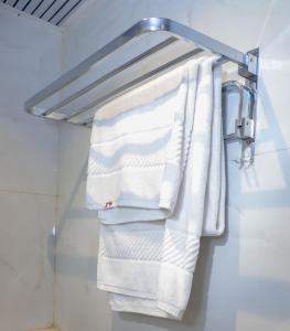 Ein Handtuchhalter mit weißen Handtüchern hängt in einem Badezimmer. in der Unterkunft Hotel Pramila in Mumbai + 65 Fotos