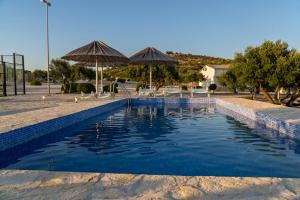 a swimming pool with chairs and umbrellas at Hacienda Nikolic in Milna