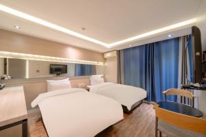 a hotel room with two beds and a desk at Busan Gwangalli SEAYOU HOTEL in Busan