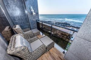 a balcony with chairs and a view of the ocean at Dyne Oceano Hotel in Jeju