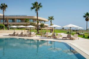 a swimming pool with lounge chairs and umbrellas at Taghazout Bay Marriott Resort in Taghazout