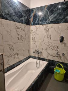 a bathroom with a bath tub with marble tiles at Vrindavan Villa Homestay in Cherambane +30 photos