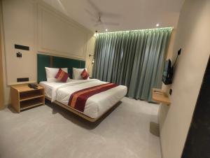 a bedroom with a bed and a window with a television at Kubo by Convivial Hotels in Raipur