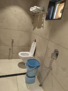 a bathroom with a toilet and a blue trash can at Kubo by Convivial Hotels in Raipur