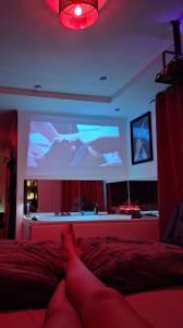 a person laying on a bed in front of a large screen at Arlove Room in Arlon