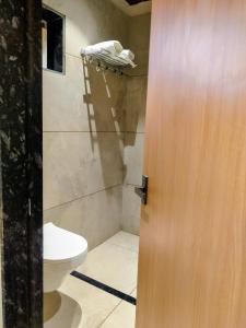 a bathroom with a toilet and a wooden door at Kubo by Convivial Hotels in Raipur +3 photos