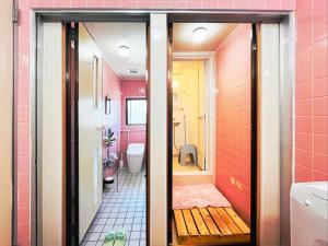 a bathroom with a toilet and pink walls at 民宿池田屋 in Taketomi
