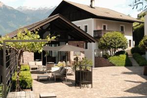 a house with a patio with chairs and an umbrella at Wine Lodge Pratenberg in Merano