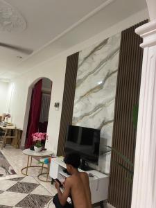 a man sitting on the floor in a living room at Villa Cempaka II in Changlun