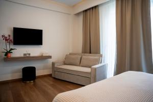 a hotel room with a chair and a television at LUMINA Luxury Suites in Missolonghi