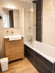 a bathroom with a shower and a sink and a tub at Apparthotel de Langogne in Langogne