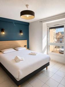 a bedroom with a large bed with a blue wall at Apparthotel de Langogne in Langogne