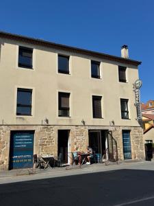 a person sitting at a table outside of a building at Apparthotel de Langogne in Langogne +4 photos