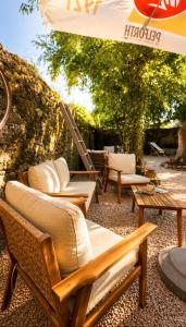 a group of wicker chairs and tables under an umbrella at Apparthotel de Langogne in Langogne