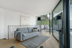 a living room with a gray couch and glass doors at Wine Lodge Pratenberg in Merano