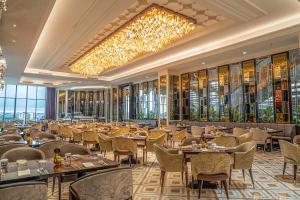 a restaurant with tables and chairs and a chandelier at The Trans Luxury Hotel Surabaya in Surabaya