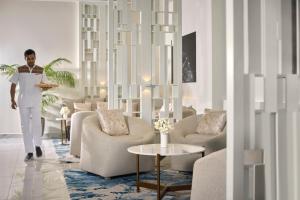 a man walking through a living room with furniture at Conrad Maldives Rangali Island in Mandhoo +82 photos
