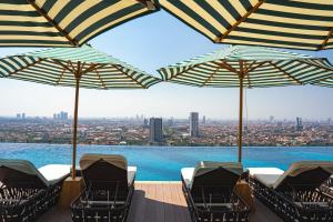 a pool with chairs and umbrellas on a deck at The Trans Luxury Hotel Surabaya in Surabaya