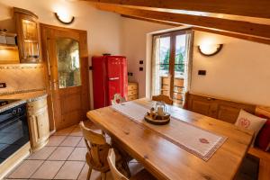 a kitchen with a wooden table and a red refrigerator at Appartamenti Pollam by AMA Val di Fassa in Pozza di Fassa