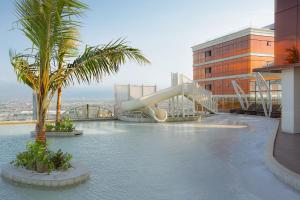 a pool with a slide and palm trees on a building at The Trans Luxury Hotel Surabaya in Surabaya