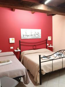a bedroom with red walls and two beds at La casetta di nonna Sesa in Viterbo