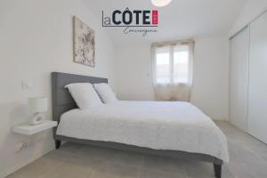 a white bedroom with a bed with white sheets at Duplex Villebois in Port-de-Bouc