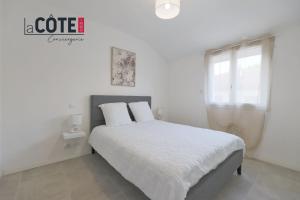 a white bedroom with a bed and a window at Duplex Villebois in Port-de-Bouc
