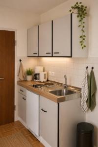 a kitchen with white cabinets and a sink at Gästehaus Stillecke in Erwitte