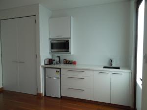 a kitchen with white cabinets and a microwave at Beach Side Garden Apartment in Perth