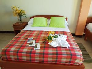 Una cama con toallas y flores encima. en Hostal Casa Cascada en Puerto Ayora