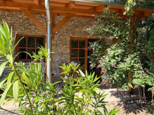 a stone house with a wooden roof and some plants at Fonfa Liget in Sénye
