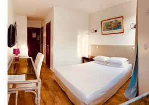a bedroom with a white bed and a desk at Tropic Hôtel in Rivesaltes