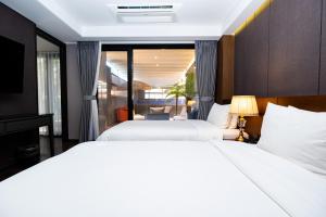 two beds in a hotel room with a window at Dyne Oceano Hotel in Jeju