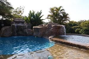 a pool with a waterfall and rocks in a backyard at Numbi Hills Self-Catering in Hazyview