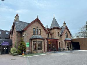 a large brick building with tables and chairs in front of it at Craigmonie Hotel Inverness by Compass Hospitality in Inverness