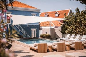 a swimming pool with a white umbrella and chairs at The Freedom Hotel in Willemstad