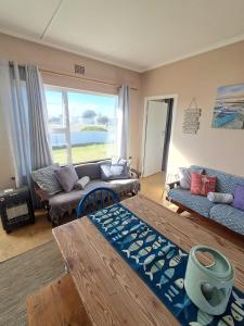 a living room with a couch and a large window at Haus Windhoek - Charming Coastal Escape in Struisbaai