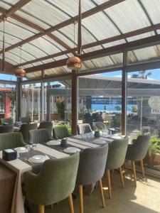 a dining room with tables and chairs and windows at Pasifik Hotel in Çeşme
