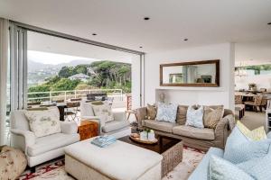 a living room with white furniture and a large window at Silvertree in Cape Town