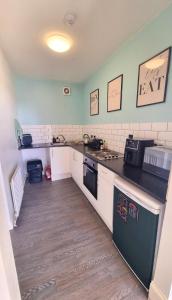 a kitchen with white cabinets and a black counter top at Lavish Lounge in Swansea