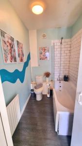 a bathroom with a tub and a toilet and a bath tub at Lavish Lounge in Swansea