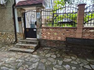 a entrance to a house with a gate and a bench at Стаи за гости Дворъ in Varna City +10 photos