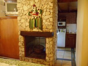 a living room with a stone fireplace in a kitchen at Cabañas El Ocio in Mar de las Pampas