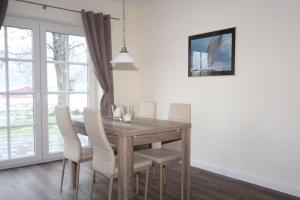 a dining room with a wooden table and white chairs at Kiek-Ut-OG-mit-Studio-Nr-3 in Haby