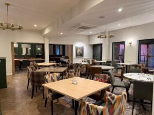 a dining room with tables and chairs and windows at Craigmonie Hotel Inverness by Compass Hospitality in Inverness