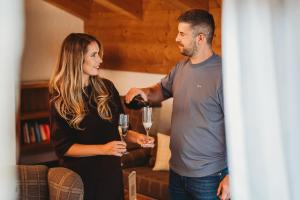 a man pouring a woman a glass of wine at Chalets Jasná Collection Centrum in Belá