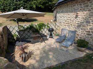 a patio with two chairs and an umbrella and a grill at Gîte du Portz in Ploërdut