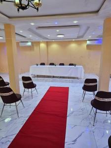 a room with a red carpet and a table and chairs at Hotel Gabu Karsa in Gabú +1 photo