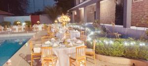 a long dining table with lights next to a pool at Hotel Gabu Karsa in Gabú